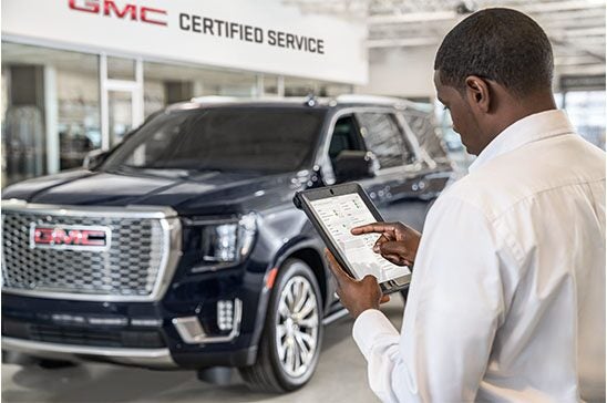 GMC Representative Standing Next to a GMC Vehicle Owner Sitting in a Certified Service Waiting Area